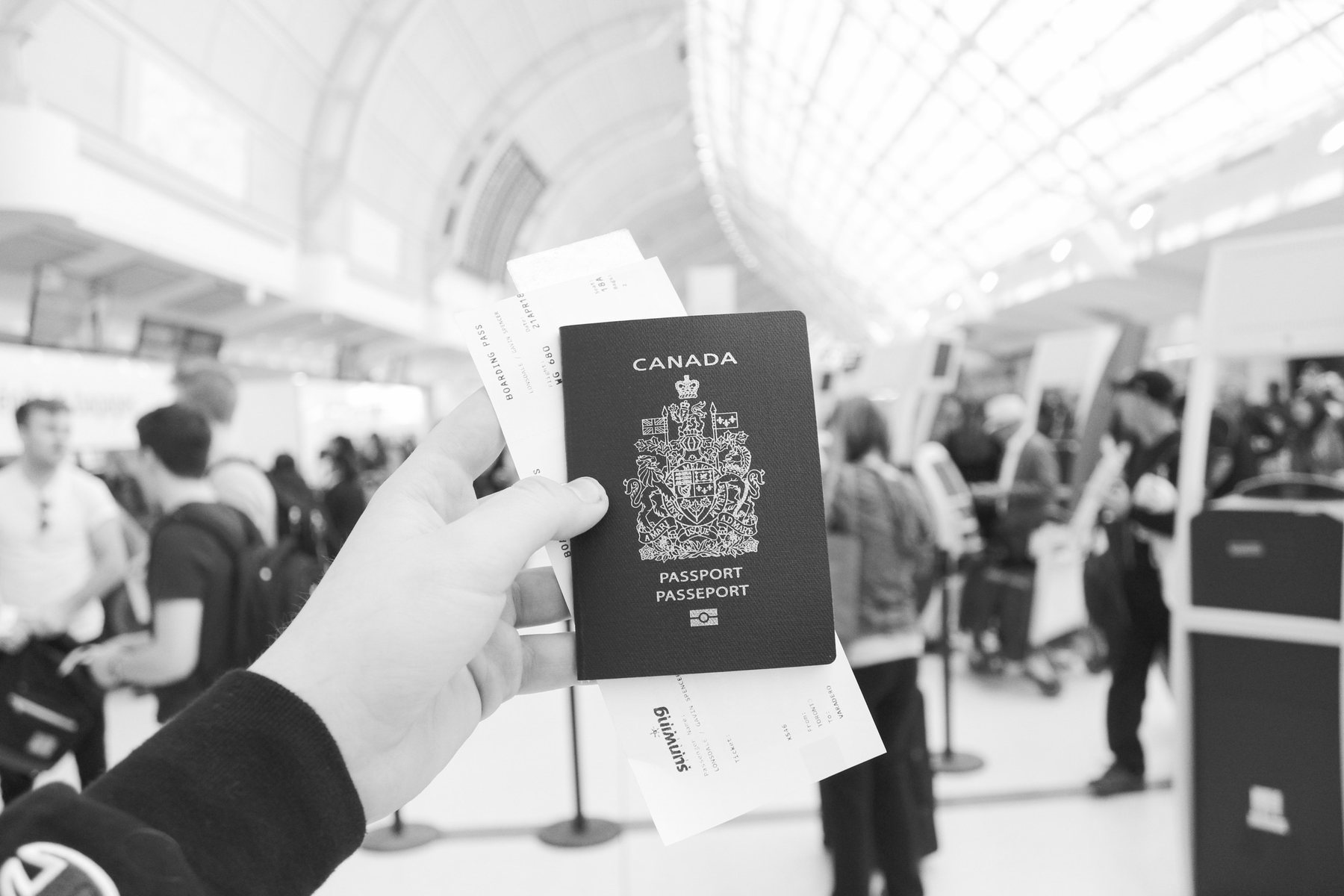 A Canadian passport and boarding pass held at an airport