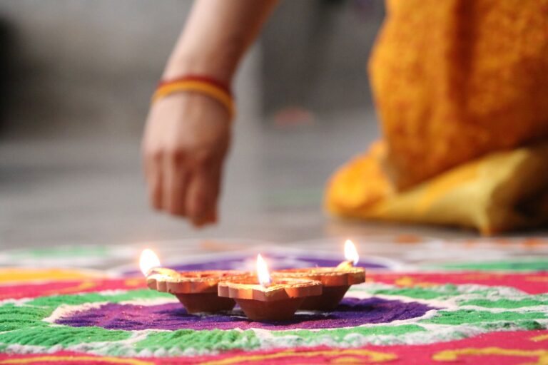 Lighting diyas on a rangoli for Diwali