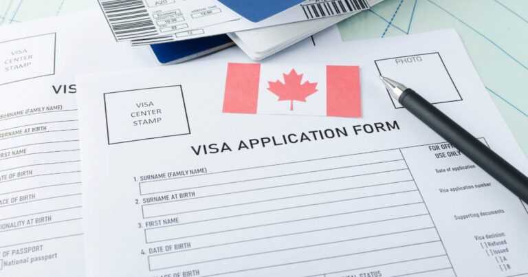 A Canadian visa application form with passport and pen